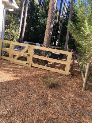 Wood and metal backyard fence with wire fencing added on the right and in the rear.