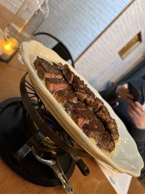 The steak is served over a burner, which melts the rich butter layer. Yum!