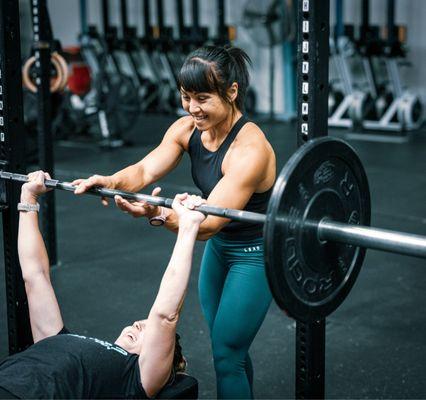 Coach Snow Charpentier, Personal trainer, helping a client with bench press