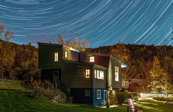 Modern home at dusk set against a swirling starry sky.