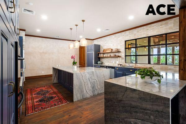 Blue Oak Kitchen remodel with navy cabinets, marble counters, wood accents, open chef's kitchen, warm hardwood floors, and artisanal lights