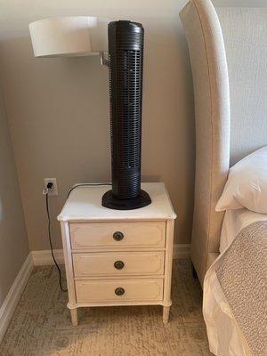 Oscillating fan on a night stand.
