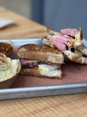 Pastrami sandwich with potato salad and baked beans.