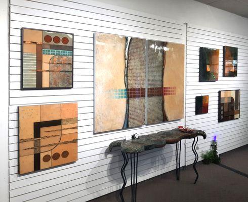 One wall of gallery with paintings in earth tones