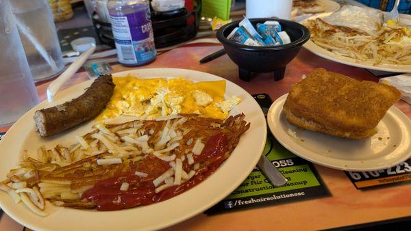 Two hard-fried scrambled eggs with American cheese, home fries, country sausage, and fresh biscuit.