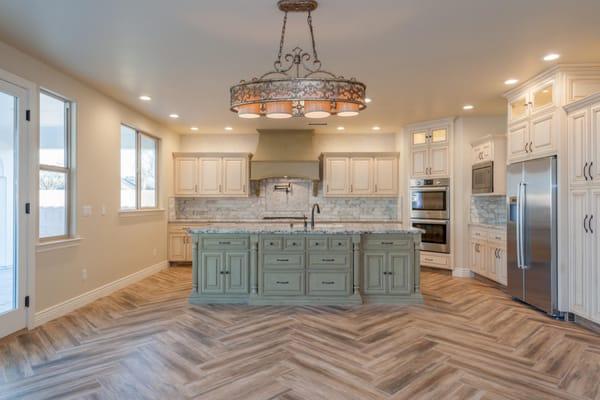 Antiqued cabinetry, marble backsplash, and herringbone wood-look tile, make this French-county kitchen spectacular.