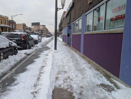 A recently cleared bike lane has snow dumped into it by a local business