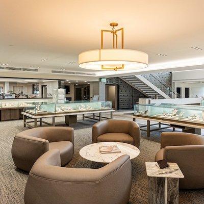 The interior of Jack Lewis Jewelers features a contemporary showroom with elegant glass display cases, cozy seating areas, an...