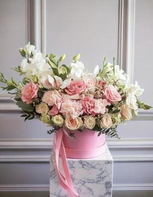 The arrangement features a stunning mix of flowers, including white and peach roses, white lisianthus, creating a harmonious blend