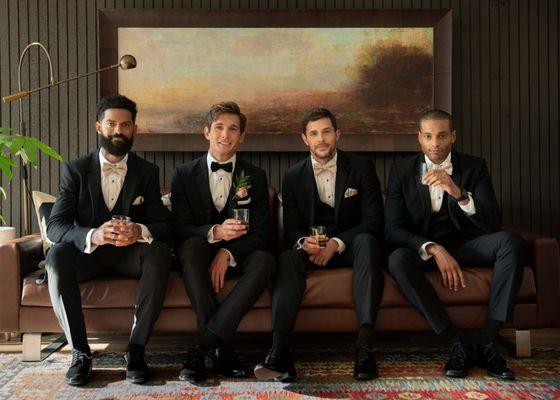 Four groomsmen in Generation Tux tuxedos sitting on a couch
