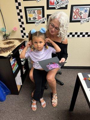 Showing off the earrings she made in art class.