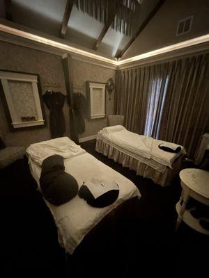 Room setup for a couple massage. They have robes and slippers hung up and I think they use them for decor.