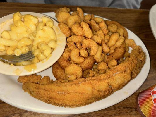 1 piece of Fried trout with popcorn shrimp, a side of Mac and cheese, and hush puppies.