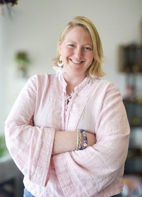 Headshot of Suzanne posing in pink shirt and crystal jewelry