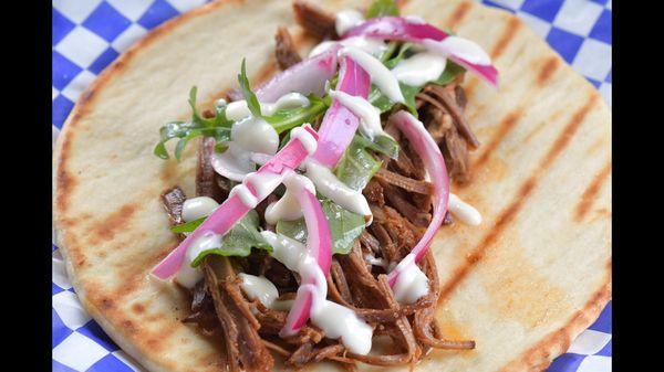 House Brisket - Slow-cooked brisket topped with a citrus arugula salad, pickled onions and horseradish mayo