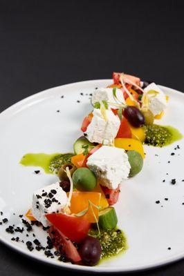 Greek salad with pesto sauce and several types of olives