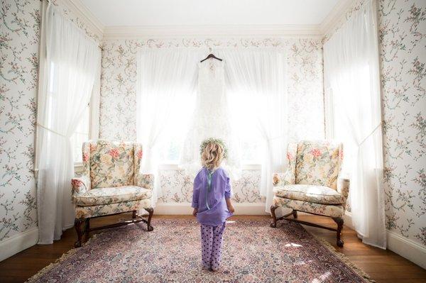 Classic Victorian New England mansion wedding. Flower girl admires beautiful gown before ceremony.