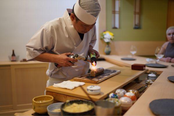 Chef Yasu using charcoal to filter out butane aroma
