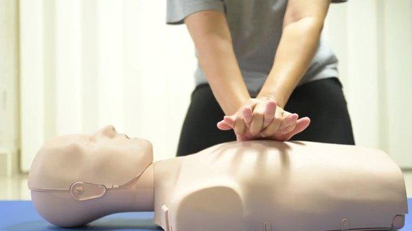Nursing student performing chest compressions on a CPR training mannequin during a hands-on Basic Life Support (BLS) class.