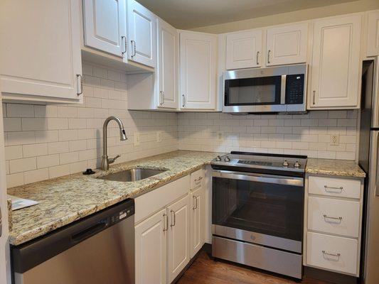 Shaker cabinets, stone countertop, tile backsplash, vinyl flooring