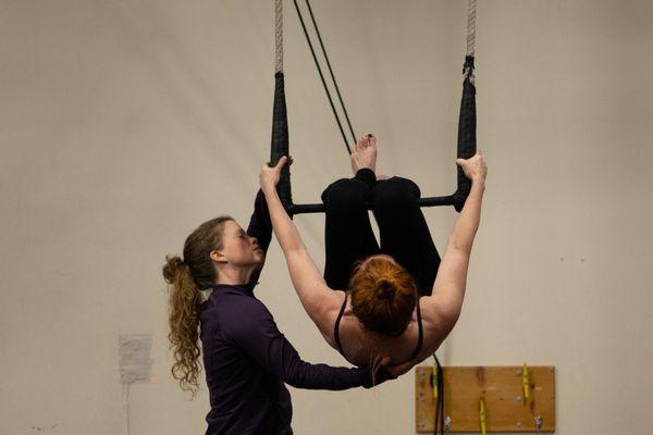 A teacher assists a student in one of Wise Fool's aerial classes