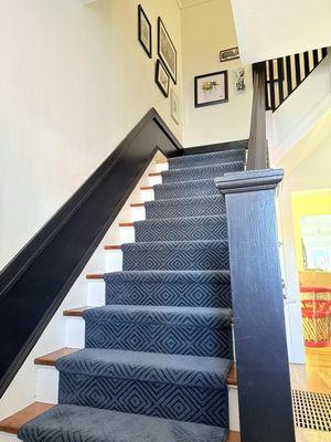 Blue stair runner on wooden stairs with black bannister