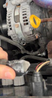 This is a picture of the alternator wire completely disconnected and dangling inside the engine bay with electrical tape wrapped around it.