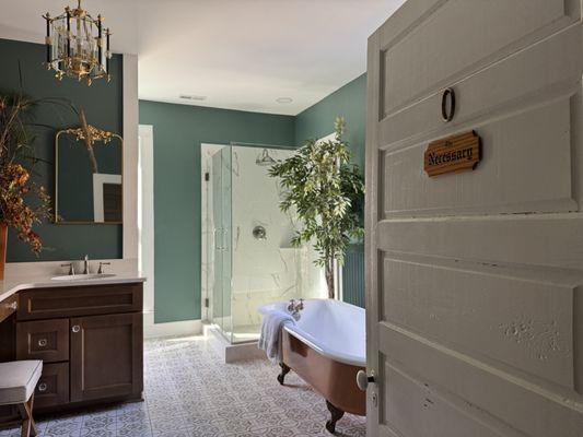 Historic 1890's bathroom remodel with mosaic tile flooring, refinished claw foot tub, tile shower and white quartz countertops.