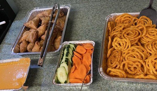 Nov, 2024. Potato and pea samosas; tomato achar; cucumbers and carrots; jalebi (dessert).