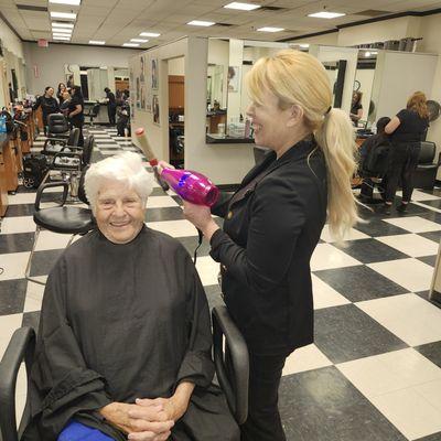 Joan Johnson smiles while Kelly styles her hair. Kelly is a great people person, not to mention a talented stylist.