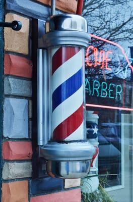Acme Barber Shop's barber pole next to the sidewalk.