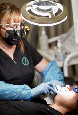 Electrologist removing hair from client's face