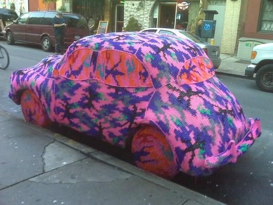 Current exhibition Olek with a knitted VW Beetle cozy on the street