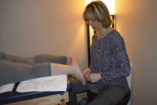 Kim using Graston Technique to release pain and tension for client.