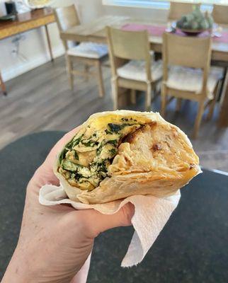 Breakfast burrito with eggs, cheese, spinach and potatoes.