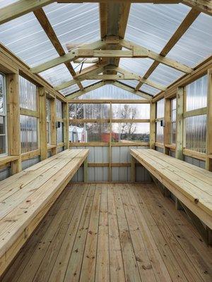 Interior of the portable greenhouse with treated wood benches, automatic roof vent and electrical with breaker box.