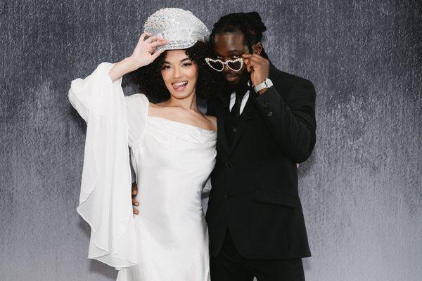A couple poses together against a dark backdrop.