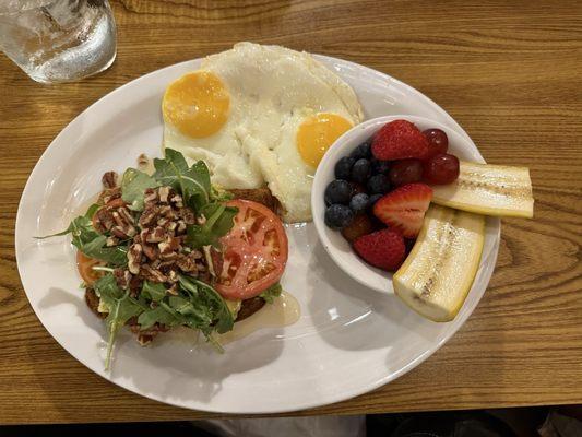 Avocado toast with tomatoes, arugula, pecans, & honey drizzle. Two eggs & fresh fruit.