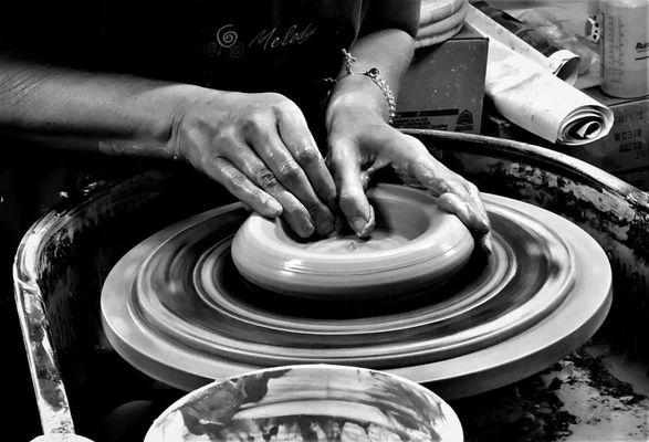 Hands throwing a pot on the wheel.