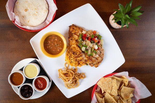 Pechuga a la Mexicana served with mexican rice, beans, crispy onions and tortillas.
