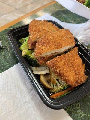 Boneless chicken on top of veggies with brown sauce