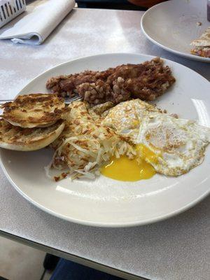 Eggs over medium, corned beef hash, hash browns and English muffin.