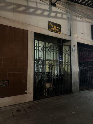 Dog outside locked overnight in the small space between the gate and storefront.