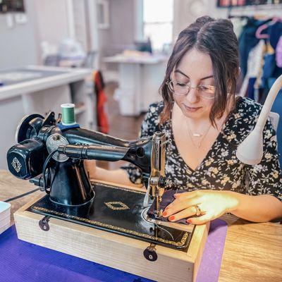 Studio Designer sewing on a vintage Singer sewing machine.