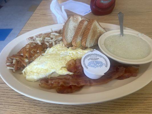 Scrambled eggs, bacon, toast and grits, and hash browns.