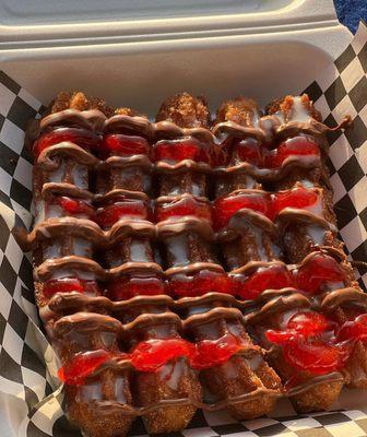 Delicious churros covered with chocolate, sweet condensed milk, and strawberry jam