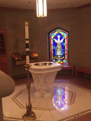 Baptismal font and stain glass window near the center of the church