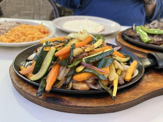 Special off-menu-allergen-free grilled chicken and veggies with beef fajitas and set up in the background.