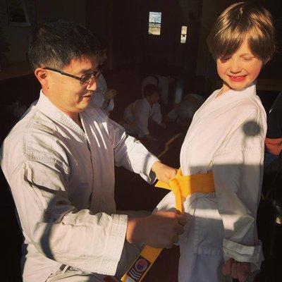 Happy Student Receiving Yellow Belt Promotion