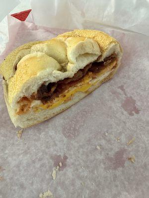 Half-eaten bacon & fried eggs on a roll.